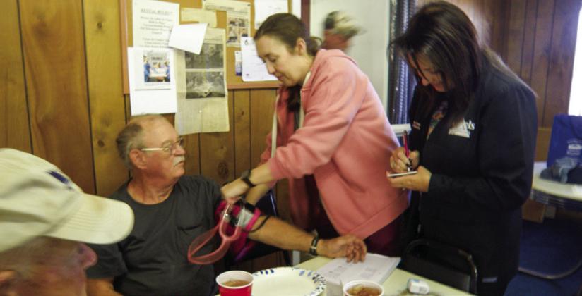 Morris Grayson, a regular attendee at the Childress Senior Citizens Center weekly luncheon, gets a blood pressure check from Angels Care Home Health of Vernon Admissions Nurse Jo Ramsey. Angels Care Home Health of Vernon Marketer Melissa Conner, right, records the blood pressure numbers for Grayson. Each participant in the blood pressure check was given a card to record future measurements.