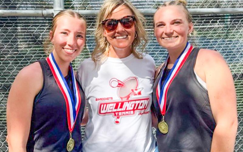 Senior Lady Rocket cousins Brynlee Proffitt, left, and Oakley Folk, right, gather with Coach Amy Inman to celebrate the recent girls’ doubles district championship. Wellington High School