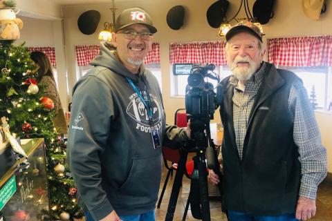 Amarillo NewsChannel 10’s video journalist Ruben Flores makes a stop at Two Rivers Family Restaurant on Highway 83 in Wellington Tuesday morning, Jan. 2. Collingsworth County Chamber of Commerce volunteer Billy Wilkerson welcomes Flores for his “Ruben on The Road” feature story concerning the hats that line the dining room wall. The Red River Sun/Bev Odom