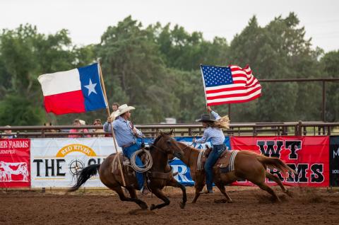 Rodeo fans rise to their feet as the father-daughter duo of Todd and Ellie Thomas carry the colors in the July 1, 2022, performance of the Wellington Fourth of July Rodeo. Witness the 2025 event scheduled for Thursday, July 3-Saturday, July 5 at the Wellington Fairgrounds. 