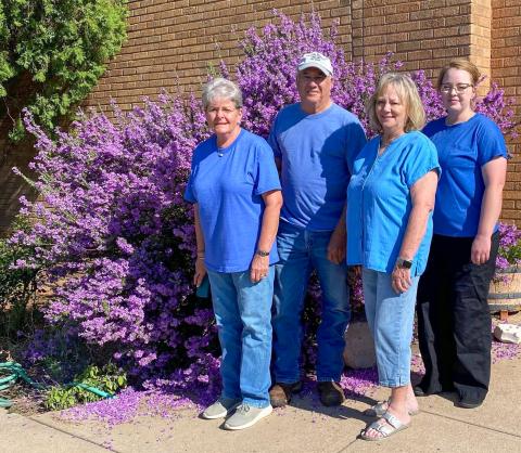 At its best bloom, the SOS from Texas crew admires the vibrant purple blooms of the Texas sage in front of the SOS shop in Samnorwood, headquartered in the former Samnorwood High School. From left: Kathie Lloyd, 15-year employee; owner Gary Oldham; Mona Darrow, 30-year employee; and Allison Bentley, five-year employee. 