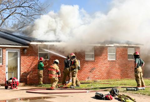 Collingsworth County Sheriff’s Office dispatchers received 911 call at 3:08 p.m. Thursday, March 19 for a house fire in the 1100 block of Haskell St. As temperatures hovered around 100 degrees, the Wellington Volunteer Fire Department responded with 13 firefighters and seven units, along with Constable Ronnie Ward, Wellington Emergency Medical Services and the Texas Department of Transportation. Flames flared up from the metal roof as firemen battled the blaze. The Red River Sun/Bev Odom