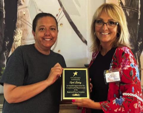 Recently licensed Registered Nurse (RN) April Lindsey accepts recognition from Wellington Care Center (WCC) Administrator Nikki Hathaway. The plaque reads, “LVN to RN Program, proudly honoring April Lindsey: In grateful appreciation for completing the requirements of Registered Nurse Licensure.” Lindsey began her 28-year journey at WCC in 1996 as a certified nurse aid (CNA). Courtesy Photo