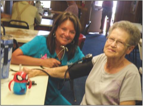 Angels Care Home Health Account Executive Melissa Conner, of Vernon, takes a blood pressure reading for Jannas Watson at the Childress Busy Beavers hamburger fundraiser Friday, June 14 at the Childress Senior Citizens Center. Photos by Grace Holman