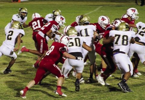 Wellington Skyrockets, including Caleb Strickland (8) and Travon Lewis (21) block out the Memphis Cyclone defensive line while ballcarrier Braylon Tarver (12) puts up yardage. The Red River Sun/Shauna Salinas