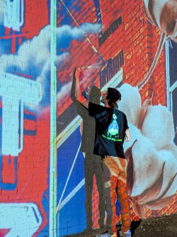 Only 28 years old, artist Malcom Byers commences his painting project at 915 West Ave. on Tuesday, June 10. The process involves using a projector at nighttime to create an outline for the expansive mural assignment. Orian Sain
