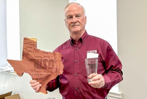 Wellington State Bank President and Chief Executive Officer (CEO) Richard Sims displays commemorative gifts given to stockholders in celebration of the bank’s 120th anniversary, including Texas-shaped cedar plaques engraved with each Wellington State Bank location and drinking glasses, each featuring the 120th anniversary mark. WELLINGTON STATE BANK