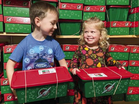 Merick Mitchell, son of Brandon and Kurby Mitchell, and Kellyn Conner, daughter of Tucker and Jordan Conner, display two of the 110 shoeboxes packed by the First Baptist Wellington congregation for delivery to impoverished children around the globe through Samaritan’s Purse Operation Christmas Child ministry. Courtesy Photo