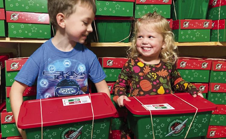 Merick Mitchell, son of Brandon and Kurby Mitchell, and Kellyn Conner, daughter of Tucker and Jordan Conner, display two of the 110 shoeboxes packed by the First Baptist Wellington congregation for delivery to impoverished children around the globe through Samaritan’s Purse Operation Christmas Child ministry. Courtesy Photo